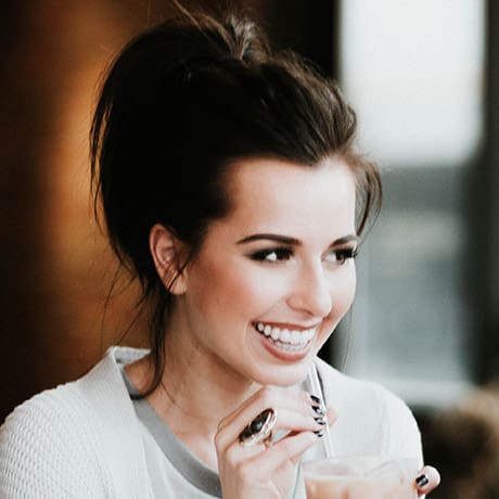 A woman smiling while holding a cup of coffee at home.
